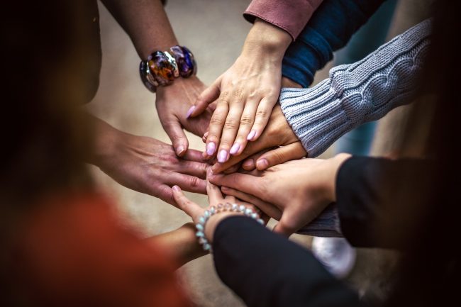 Group of 7 hands touching in a circular pattern.